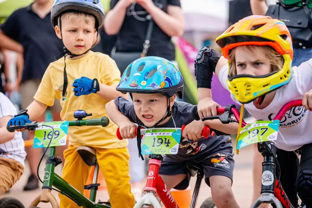 Kinder mit Helmen auf Laufrädern vor dem Start
