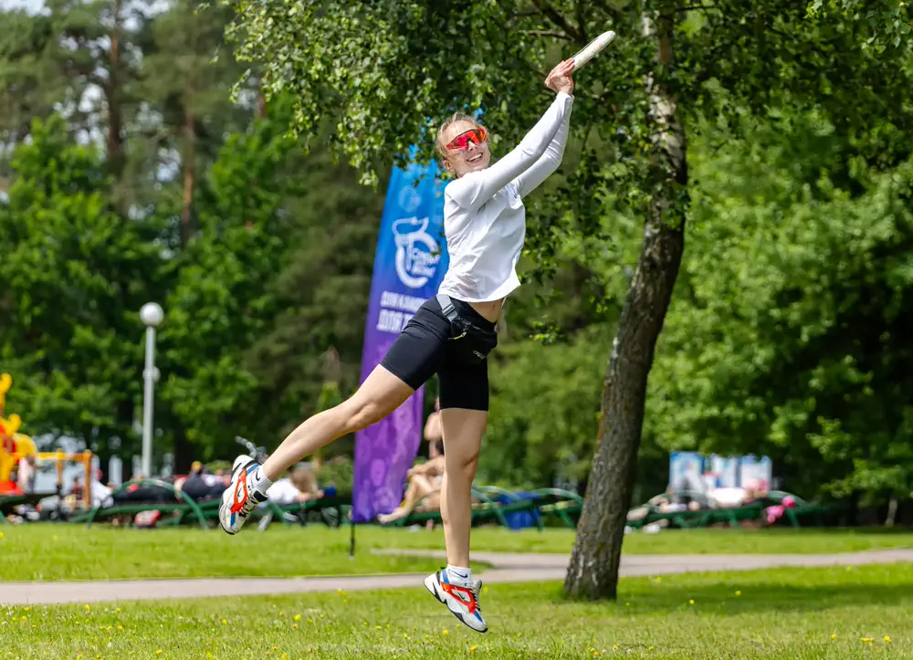 Sportlerin beim Sprung und Wurf einer Flugscheibe im Park